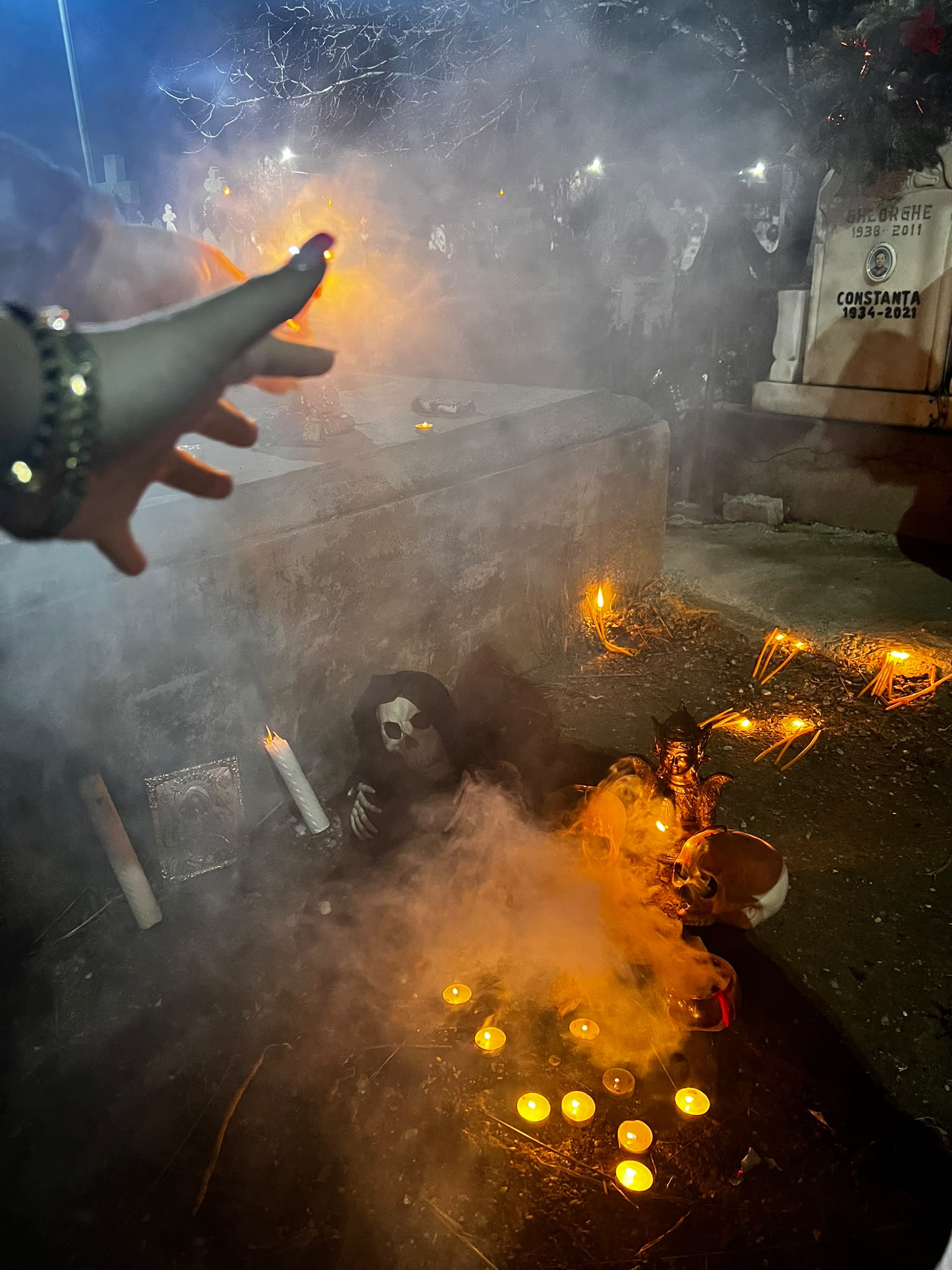 Lumânare aprinsă într-un ritual de noapte, în ceață