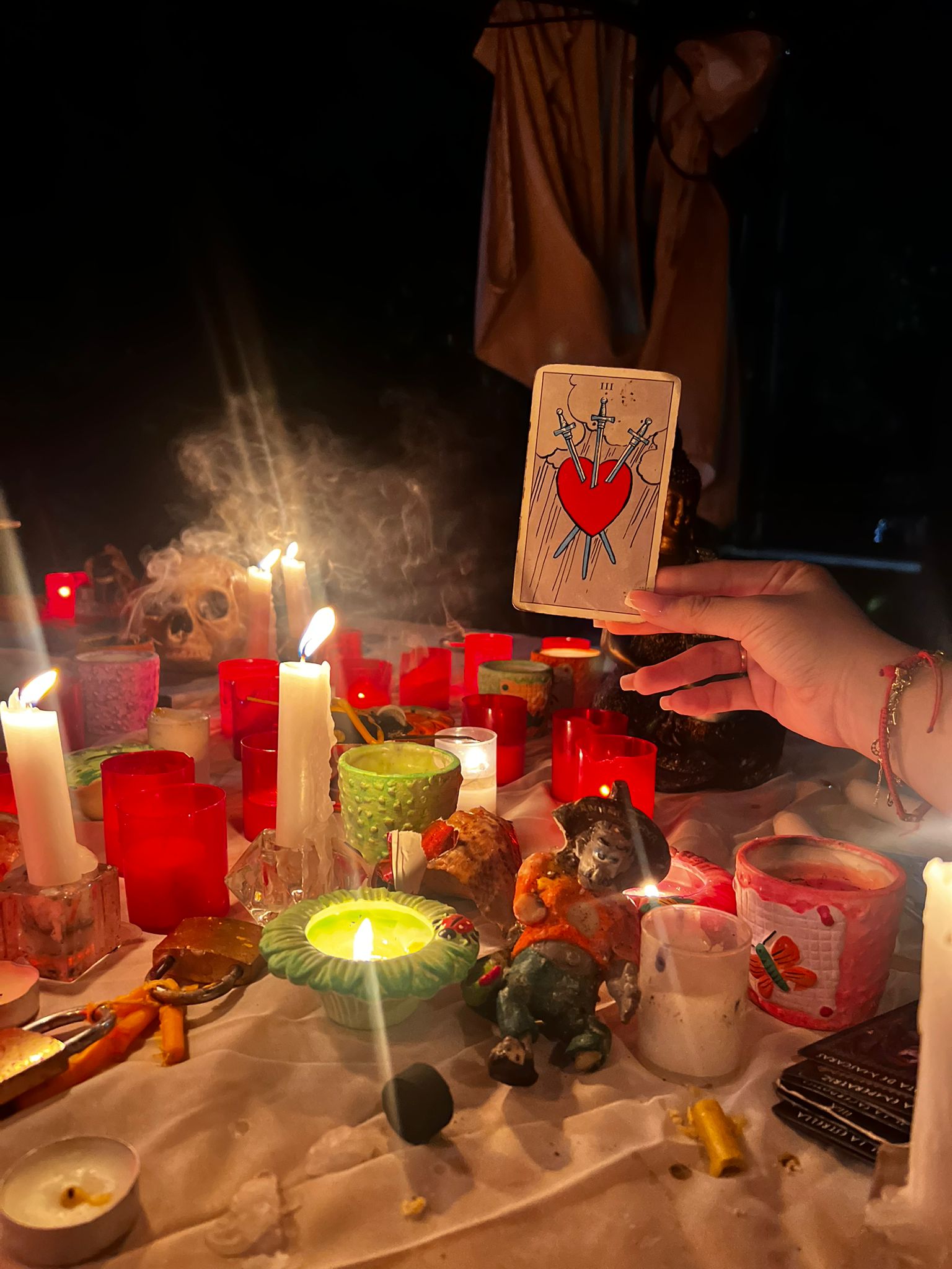 Carte de tarot ținută deasupra altarului, printre lumânări
